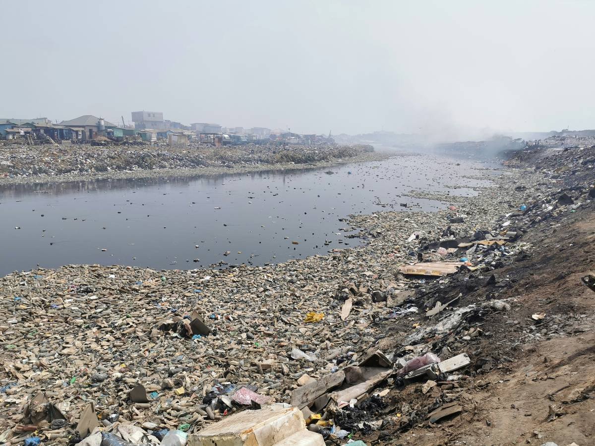 a large amount of trash is on the shore of a river