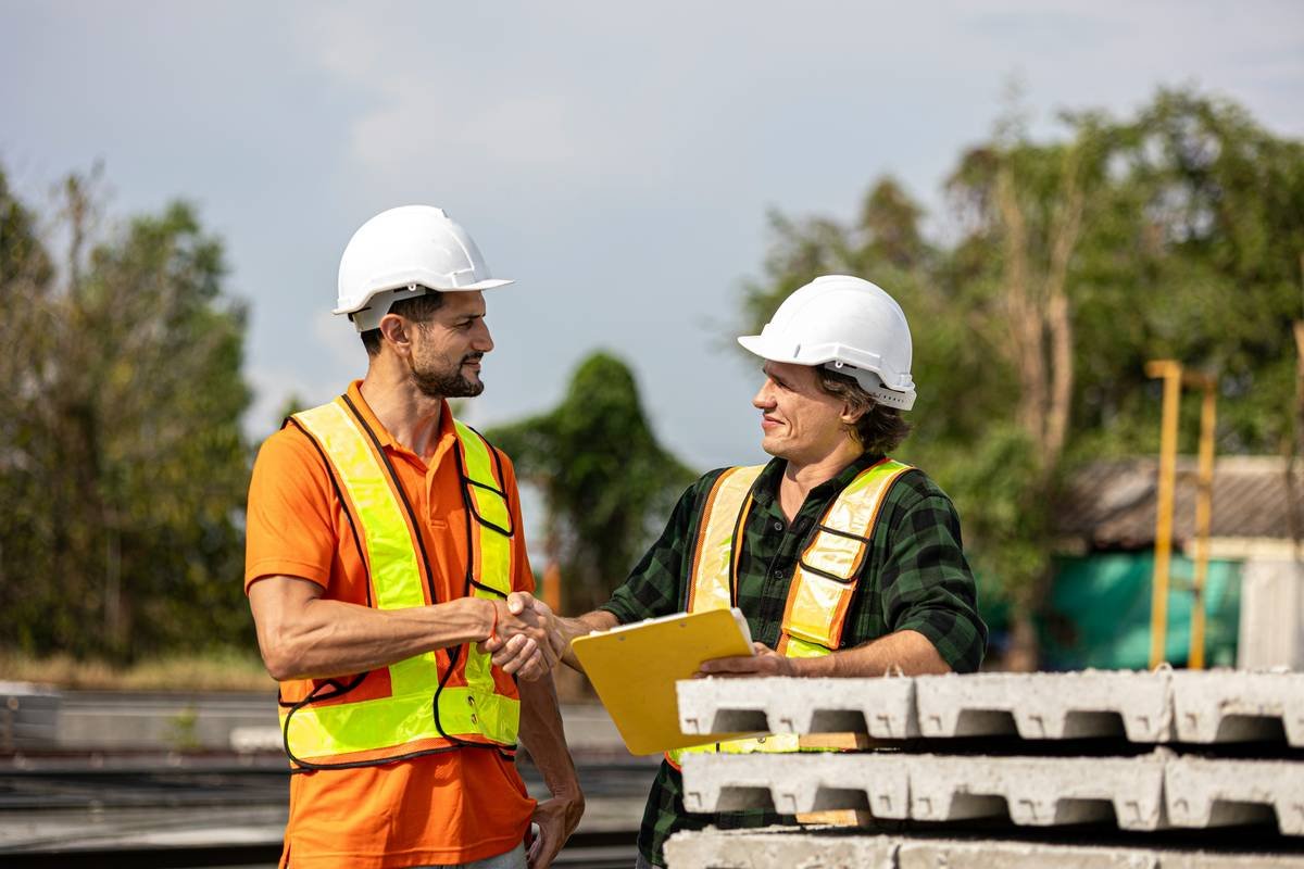 Two male engineers from different cultures work together in a floor making factory. Senior supervisor discusses with his engineer or coworker checking the concrete wall production system
